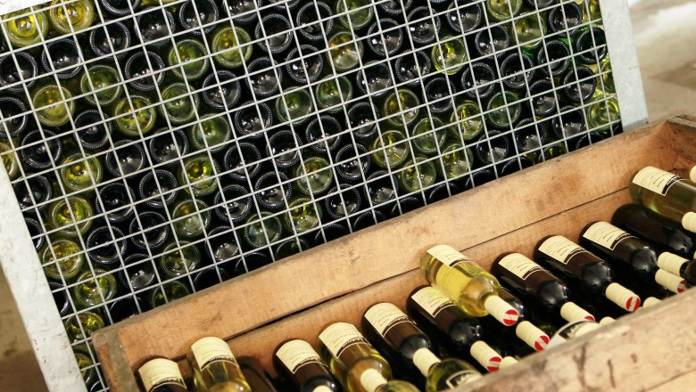 Heurigenlokal Familie Schabasser, © weinfranz.at Weinflaschen in einem Gitterregal und einer Holzkiste.