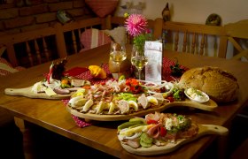 Heurigenjause, © Oberaigner Ein Tisch mit einer Heurigenjause: Aufschnitt, Käse, Brot und Wein.