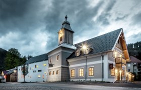 Hotel zum Glockenturm, © www.croce.at Ein Hotel mit Glockenturm bei bewölktem Himmel, beleuchtet von Straßenlaternen.