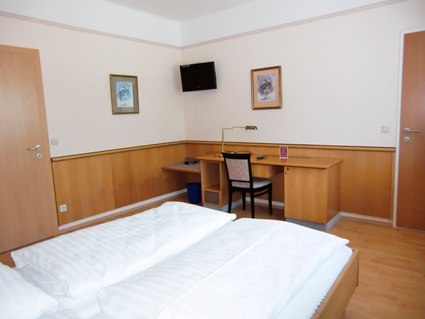 Double room, © Weinberger A hotel room with double bed, desk, chair and wall decoration.