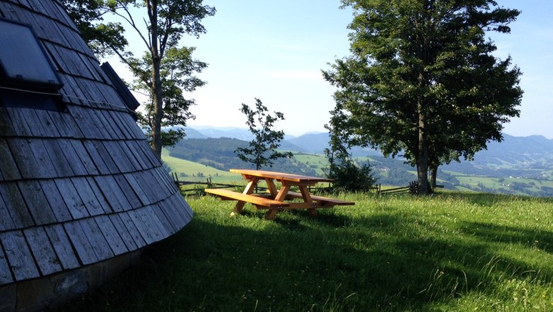 Klanggarten, © Mostviertel Tourismus Holzhütte und Picknicktisch auf einer Wiese mit Bäumen und Bergblick.