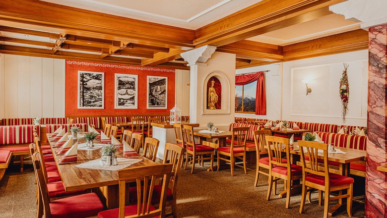 Family business since 1897, © Niederösterreich Werbung/Klaus Engelmayer Cozy dining room with wooden furniture and red and white striped upholstery.