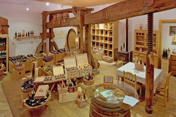 Weingut Holzer AbHofLaden, © Weingut Holzer Innenansicht eines Weinguts mit Regalen voller Weinflaschen und rustikaler Einrichtung.