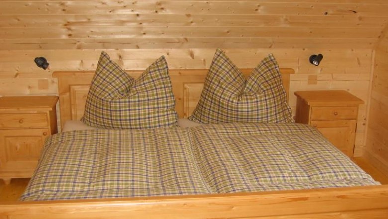 Lassing-Hochkar vacation village, © Feriendorf Lassing Wooden bedroom with checkered double bed and bedside tables.