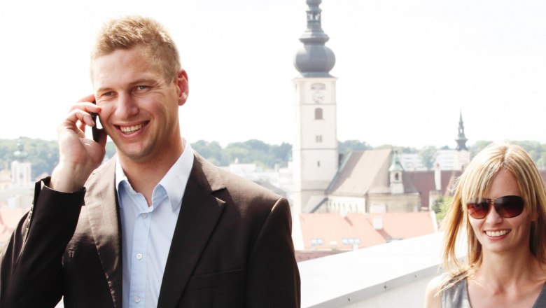 Convention Bureau St. Pölten, © schwarz-koenig.at Two people on a terrace with a view of St. Pölten, a church in the background.