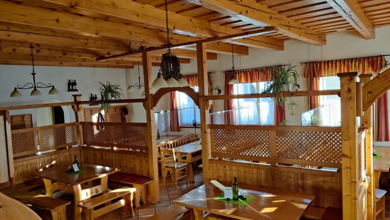 Wine tavern, © Familie Poyntner Interior view of a rustic wine tavern with wooden furniture and plants.