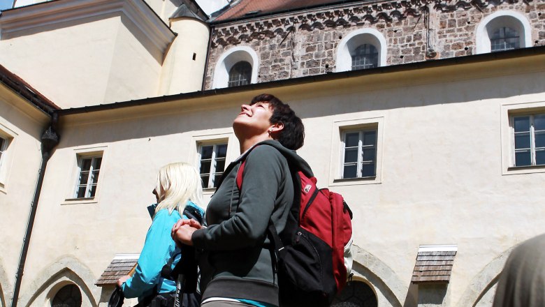 Lilienfeld Abbey, © Mostviertel Tourismus/Weinfranz.at Two people with rucksacks and hiking poles stand in front of Lilienfeld Abbey and look up.