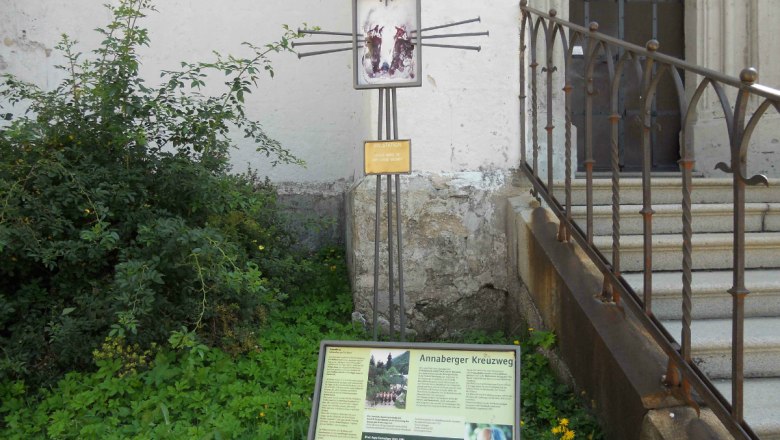 Annaberg Way of the Cross, © Gemeinde Annaberg A sign with information about the Annaberg Way of the Cross next to a staircase and plants.