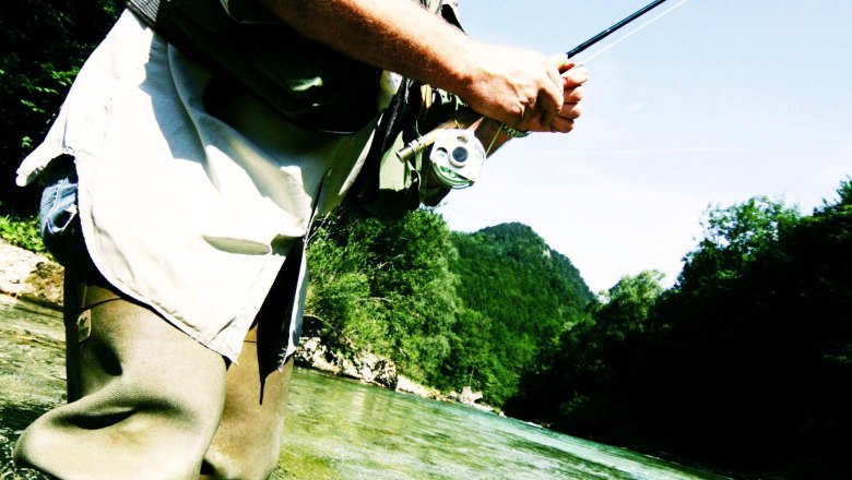 Fly fishing Opponitz, © Mostviertel Tourismus/Weinfranz.at A man fly fishing in a river, with a jumping fish in the foreground.
