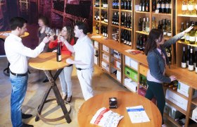 Menschen in einem Weinladen, die Wein probieren und Flaschen auswählen.