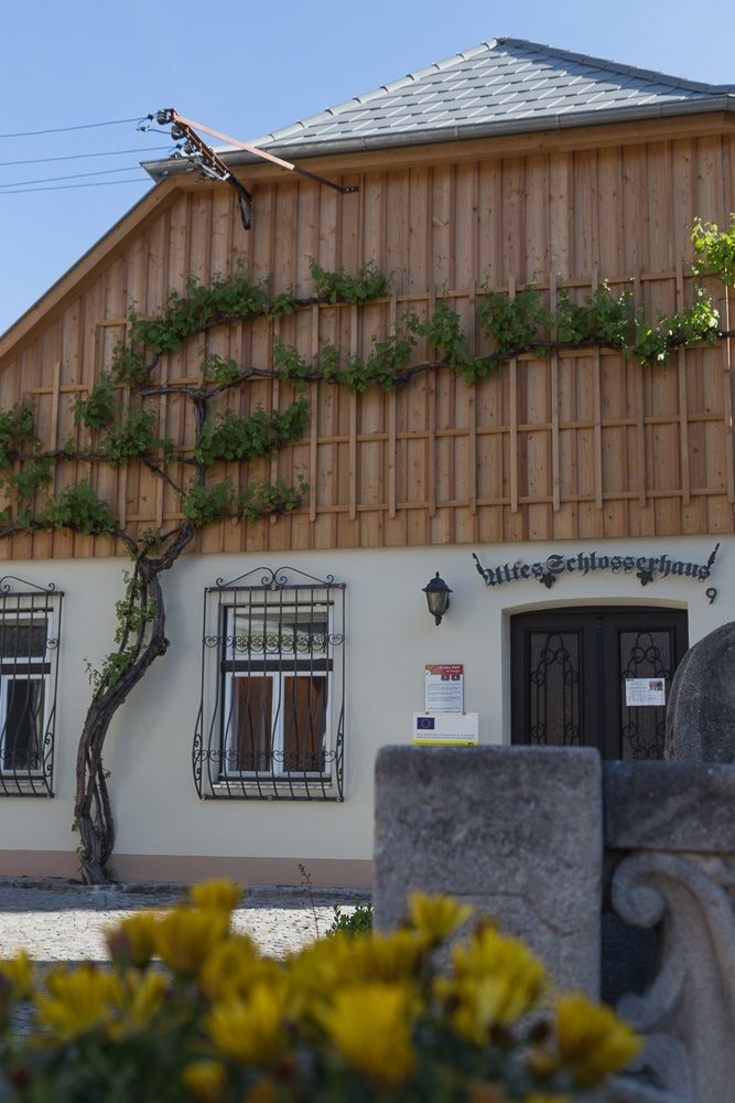 Fassade eines alten Schlosserhauses mit Holzverkleidung und Kletterpflanzen.