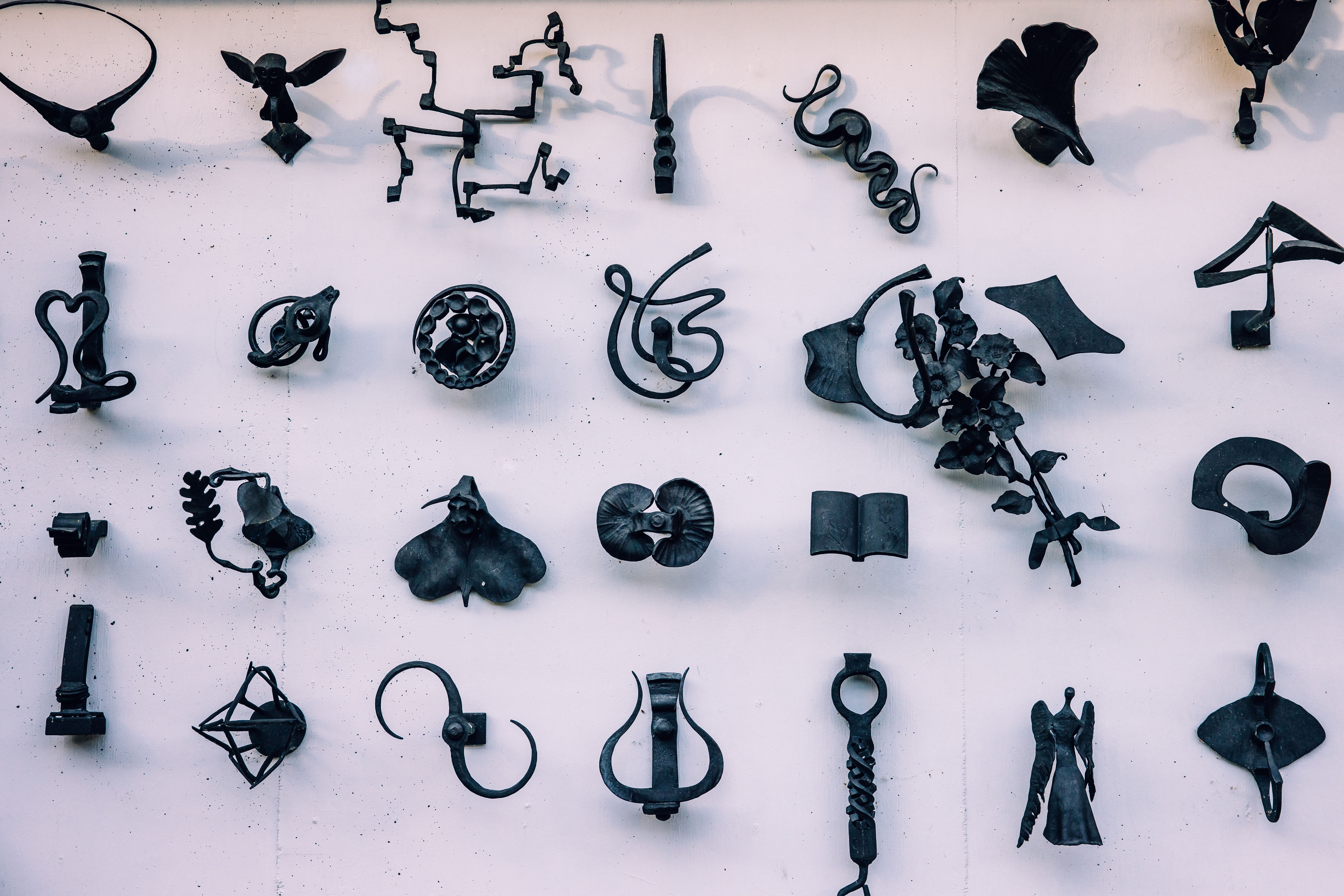 Ausstellung kunstvoll geschmiedeter Eisenobjekte in unterschiedlichen Formen und Motiven an einer Wand entlang der Schmiedemeile in Ybbsitz.