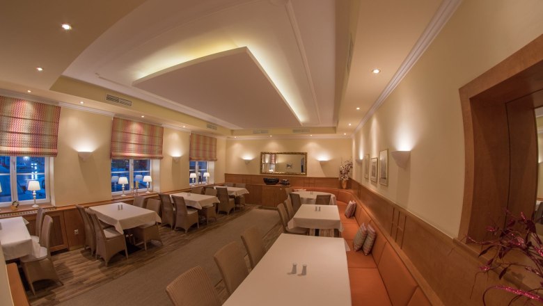 Elegantes Restaurant mit gedeckten Tischen, warmem Licht und stilvoller Dekoration.