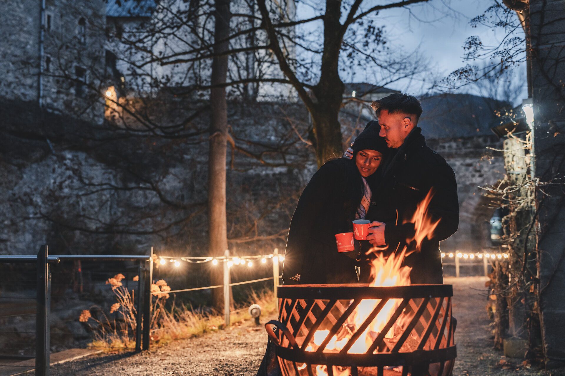 Paar genießt die Wärme des lodernden Feuerkorbs.