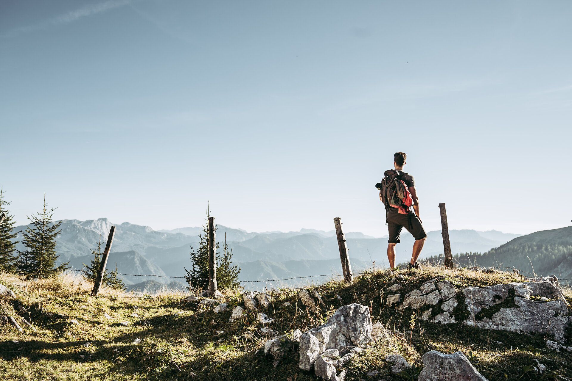 Die sanften Hügel der Ybbstaler Alpen erstrecken sich majestätisch im Hintergrund, während ein Wanderer inmitten der Natur verweilt. Die klare Luft und die atemberaubende Aussicht laden dazu ein, die Seele baumeln zu lassen und die Schönheit der Berglandschaft zu genießen.