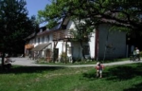 Ein traditionelles Bauernhaus mit Holzbalkon und grünem Garten im Vordergrund.