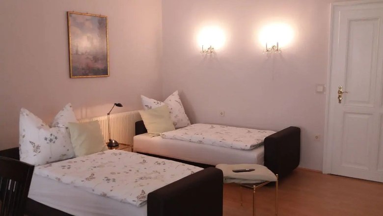 Zwei Einzelbetten in einem hellen Raum mit Wandlampen und einem Gem&auml;lde an der Wand.