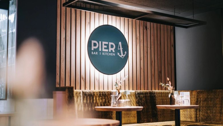 Innenansicht des Restaurants Pier 4 mit Holzwand und Logo.