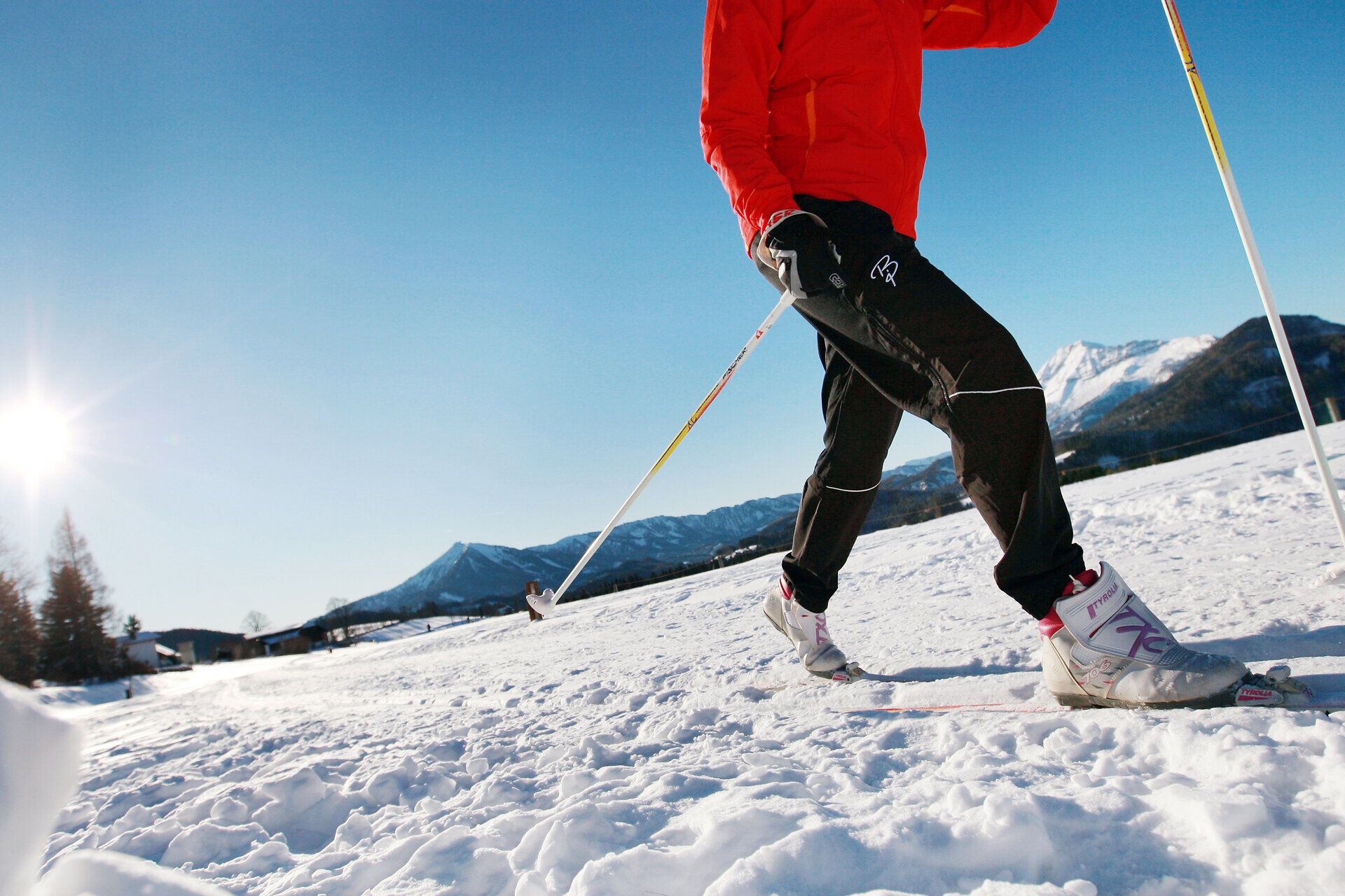 In der klaren Winterluft gleitet eine Frau elegant über die schneebedeckten Loipen, umgeben von majestätischen Bergen. Die strahlende Sonne wirft glitzernde Lichtreflexe auf den Schnee und schafft eine zauberhafte Atmosphäre, die zum Verweilen einlädt. Hier im Mariazellerland wird Langlaufen zu einem unvergesslichen Erlebnis inmitten der unberührten Natur.