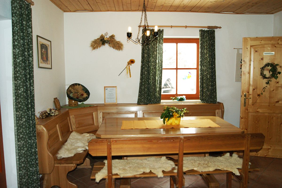 Gemütlicher Aufenthaltsraum mit Holzmöbeln, Tisch, Eckbank und Dekorationen an der Wand.