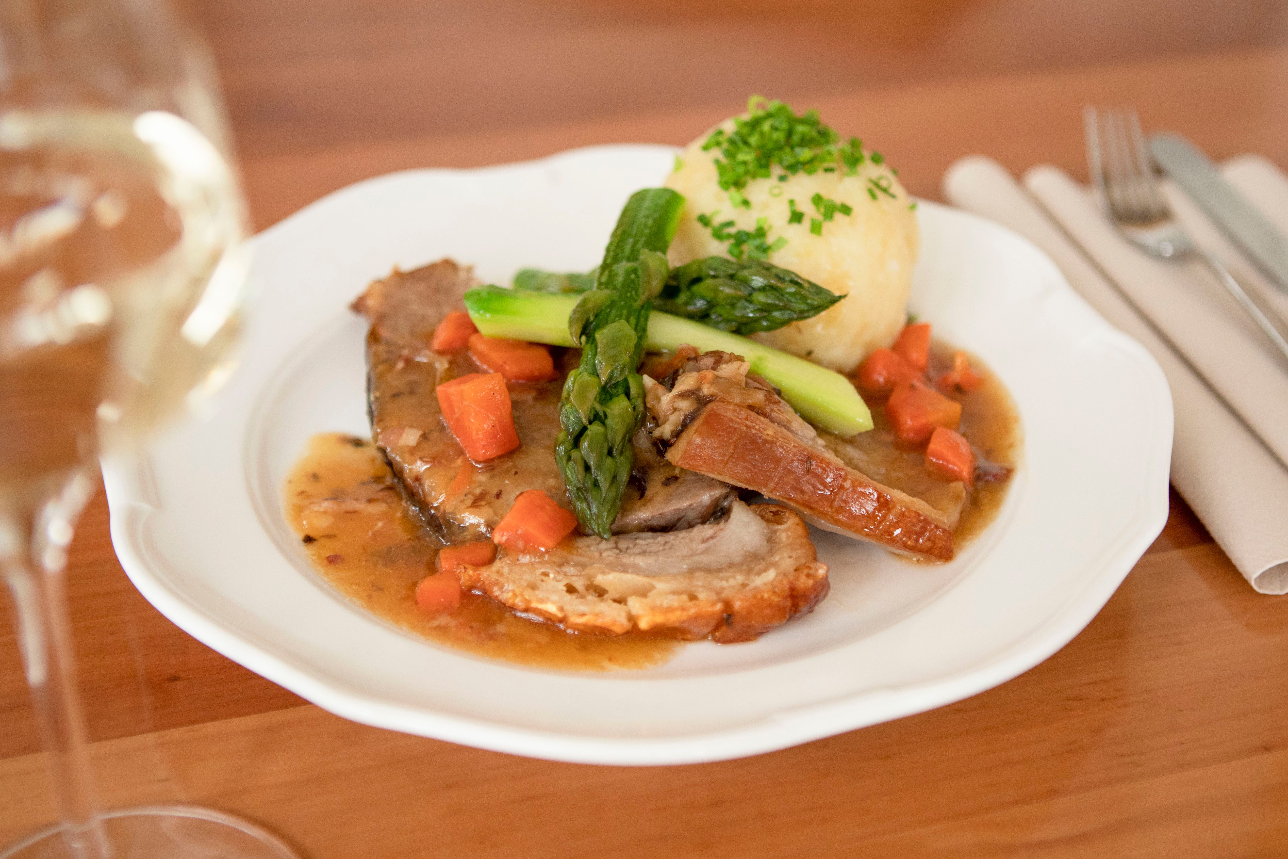 Mostviertler Mostbratl serviert mit Erdäpfelknödel und grünem Spargel.