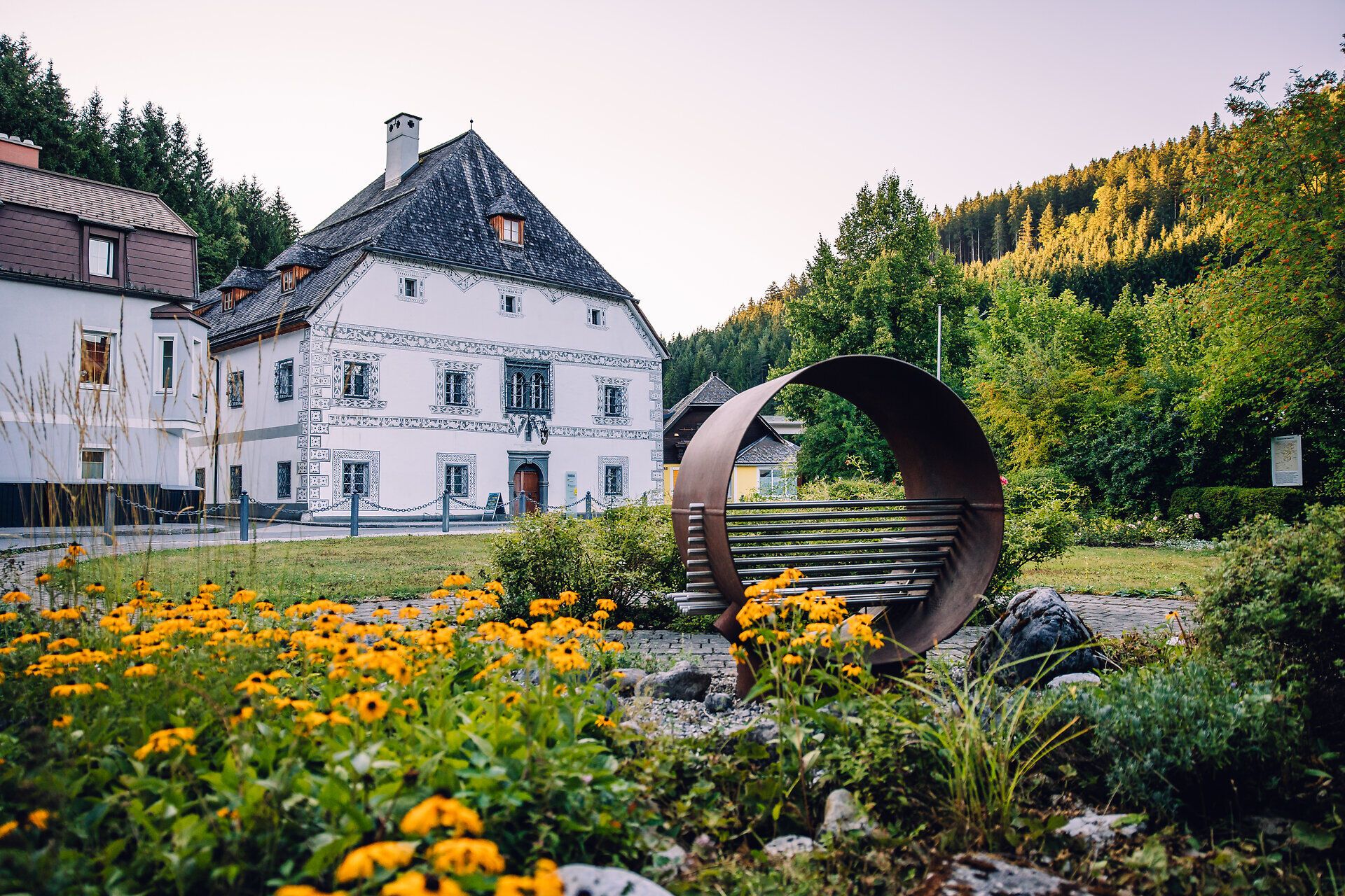 Hammerherrenhaus in Lunz am See mit historischem Gebäude, Gartenanlage und bewaldeter Bergkulisse.