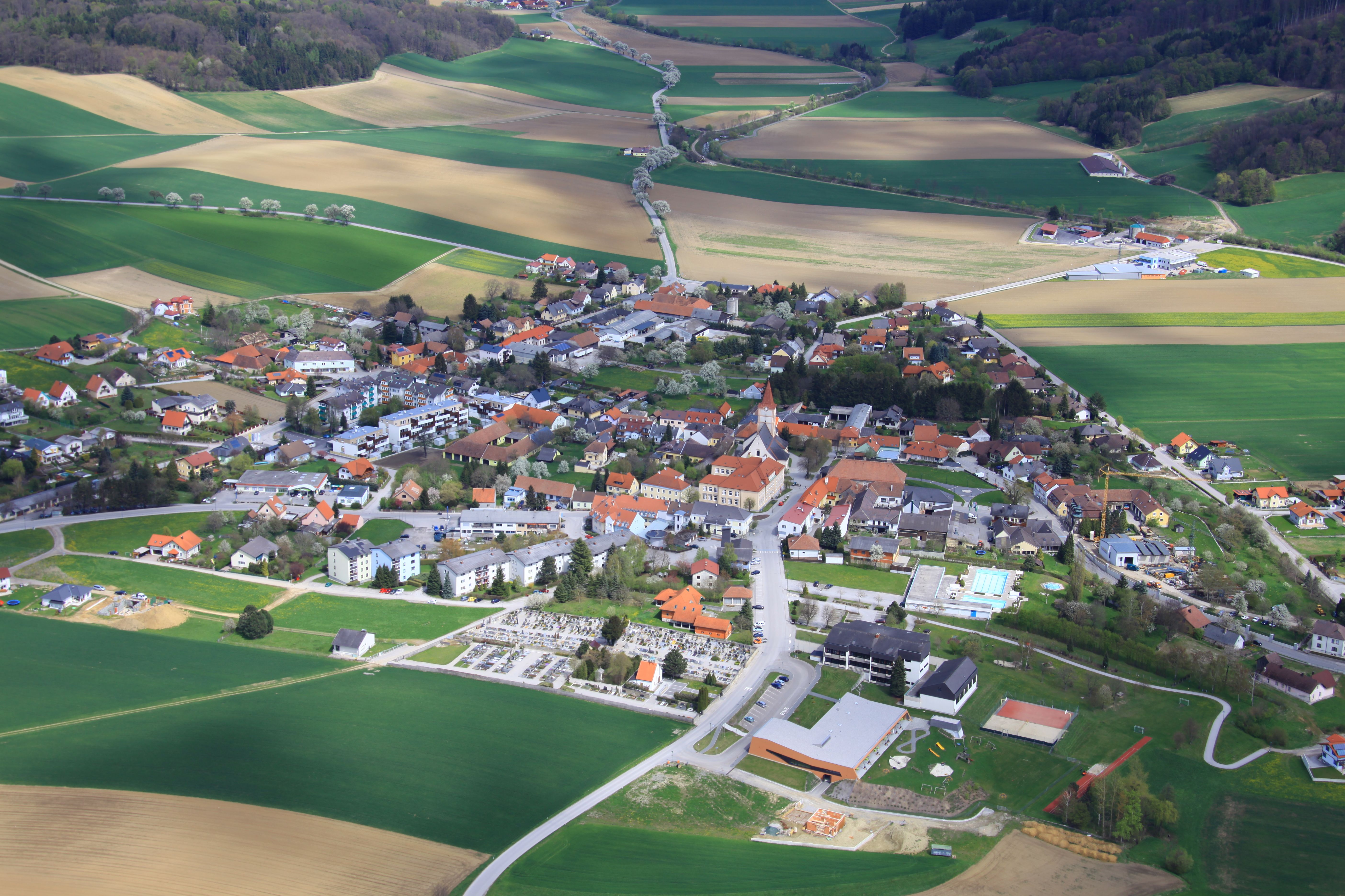 Luftaufnahme der Gemeinde Pyhra mit Feldern und Gebäuden.