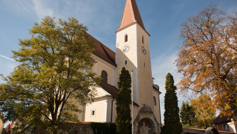 Church with tower and clock, surrounded by trees in the fall.