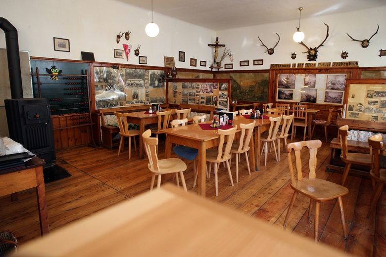 Innenansicht einer rustikalen Gaststube mit Holzmöbeln und Wanddekorationen.