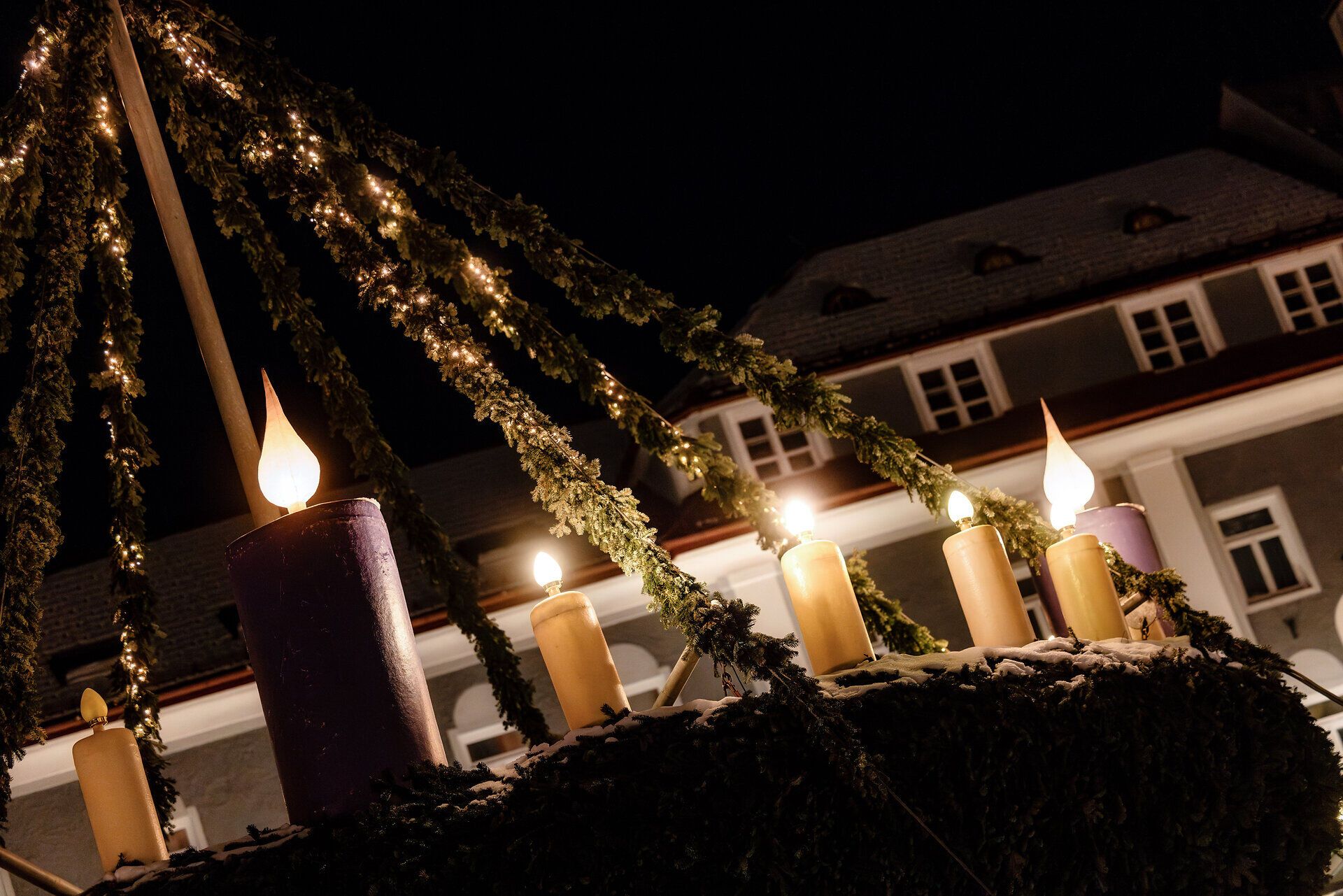 In der festlich geschmückten Adventszeit erstrahlt der Ort in warmem Licht, während die großen Kerzen auf dem Adventskranz eine besinnliche Atmosphäre schaffen. Die winterliche Kulisse lädt dazu ein, die Vorfreude auf Weihnachten zu genießen und die zauberhafte Stimmung zu erleben.