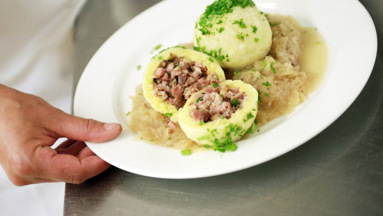 Ein Teller mit gefüllten Knödeln auf Sauerkraut, garniert mit Petersilie.