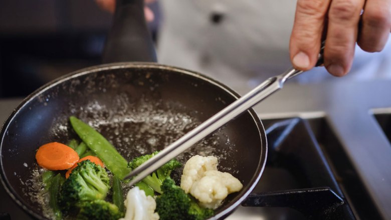 Cook stirs vegetables in a pan.
