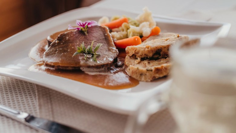 A plate of roast beef, bread dumplings and vegetables.
