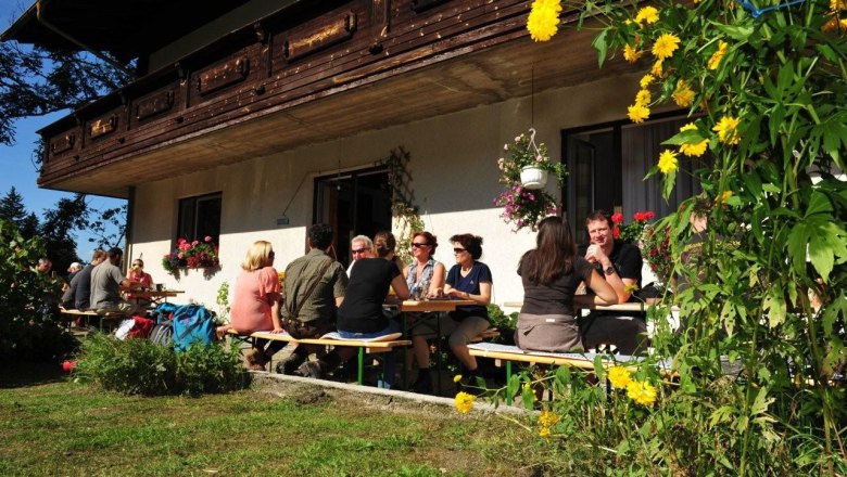 People sit at tables outside a farmhouse.
