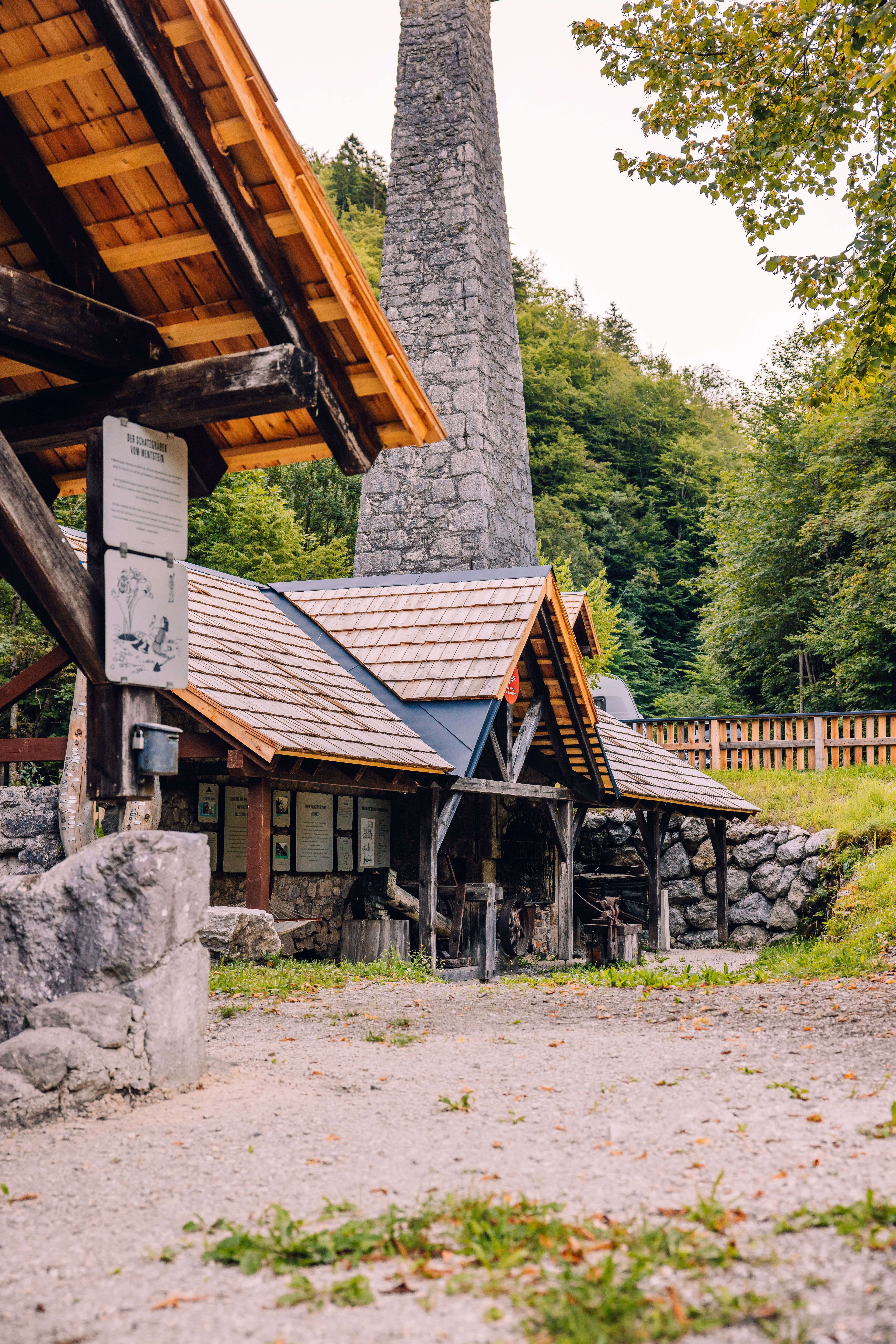 Wentsteinhammer in Hollenstein mit steinernem Schornstein, Holzüberdachungen und Infotafeln im Wald.