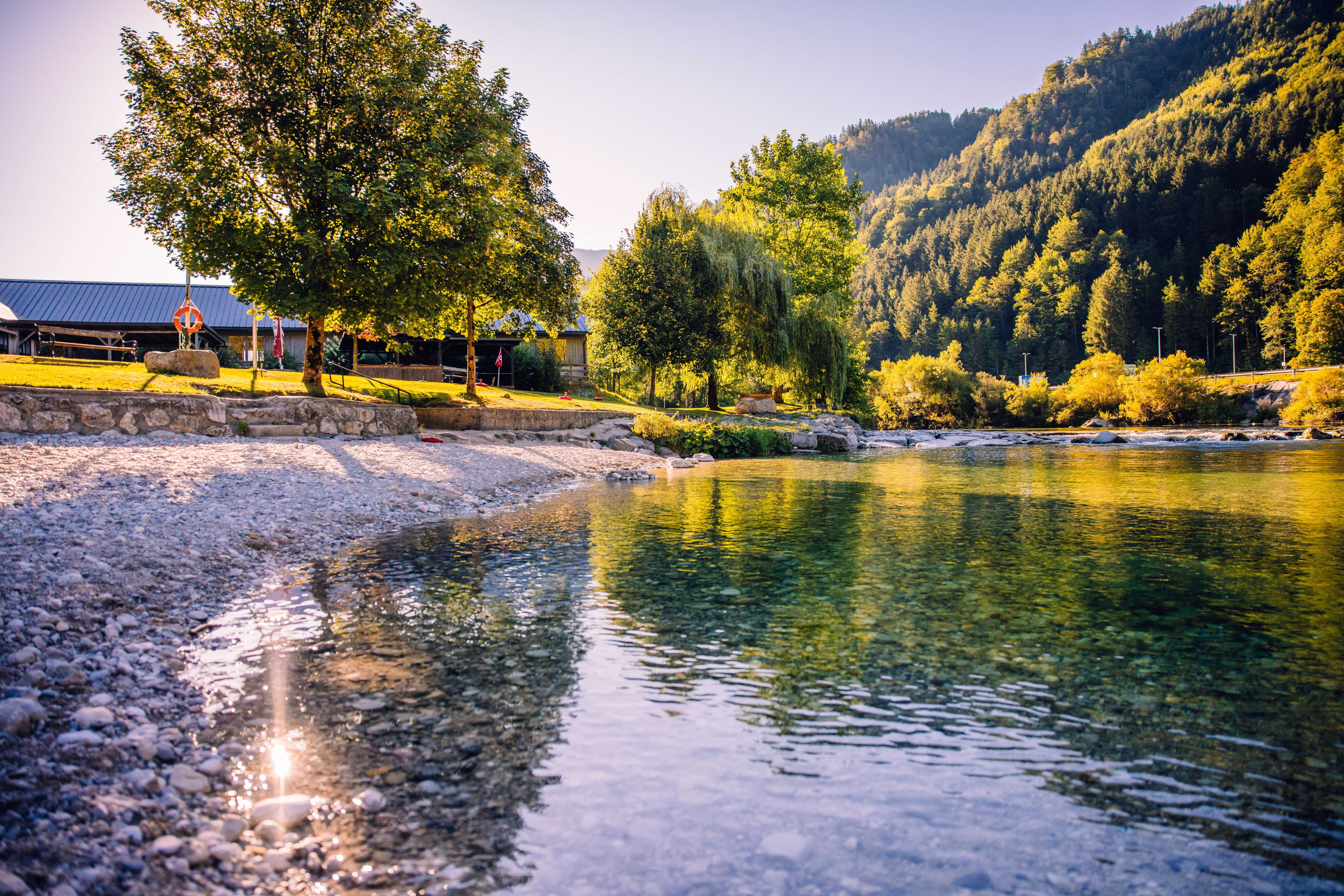 Naturbadestelle an der Ybbs in Hollenstein mit Kiesstrand, klarem Wasser und bewaldeten Bergen im Hintergrund.