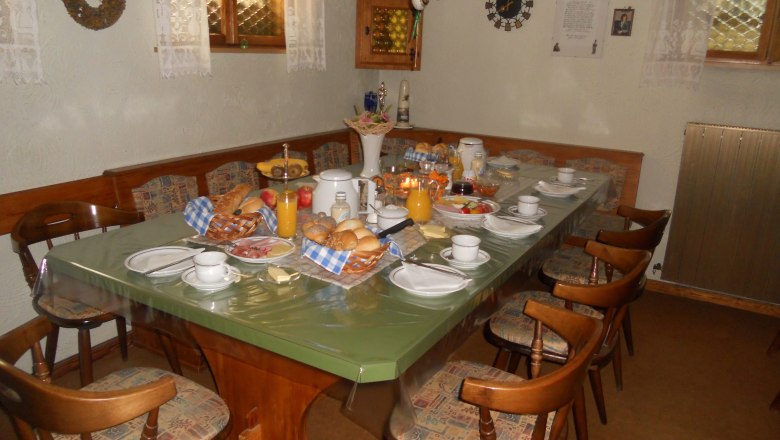 Breakfast room with a table and chairs. An extensive breakfast is laid out at the table.