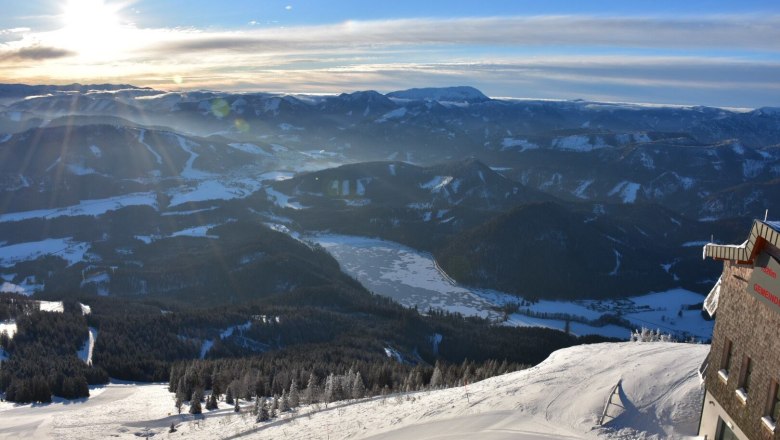 Winterlandschaft mit schneebedeckten Bergen und dem gefrorenen Erlaufsee im Sonnenuntergang.