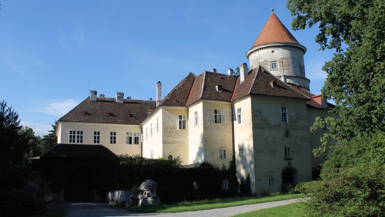Schloss in Pyhra mit Turm und Garten bei sonnigem Wetter.
