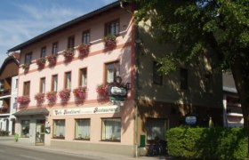 A traditional inn with a pink façade and flower boxes on the windows.