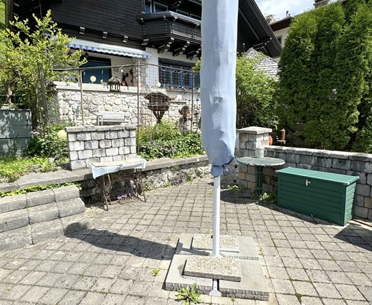 gepflasterter Sitzplatz im Garten mit Sonnenschirm und Grillm&ouml;glichkeit