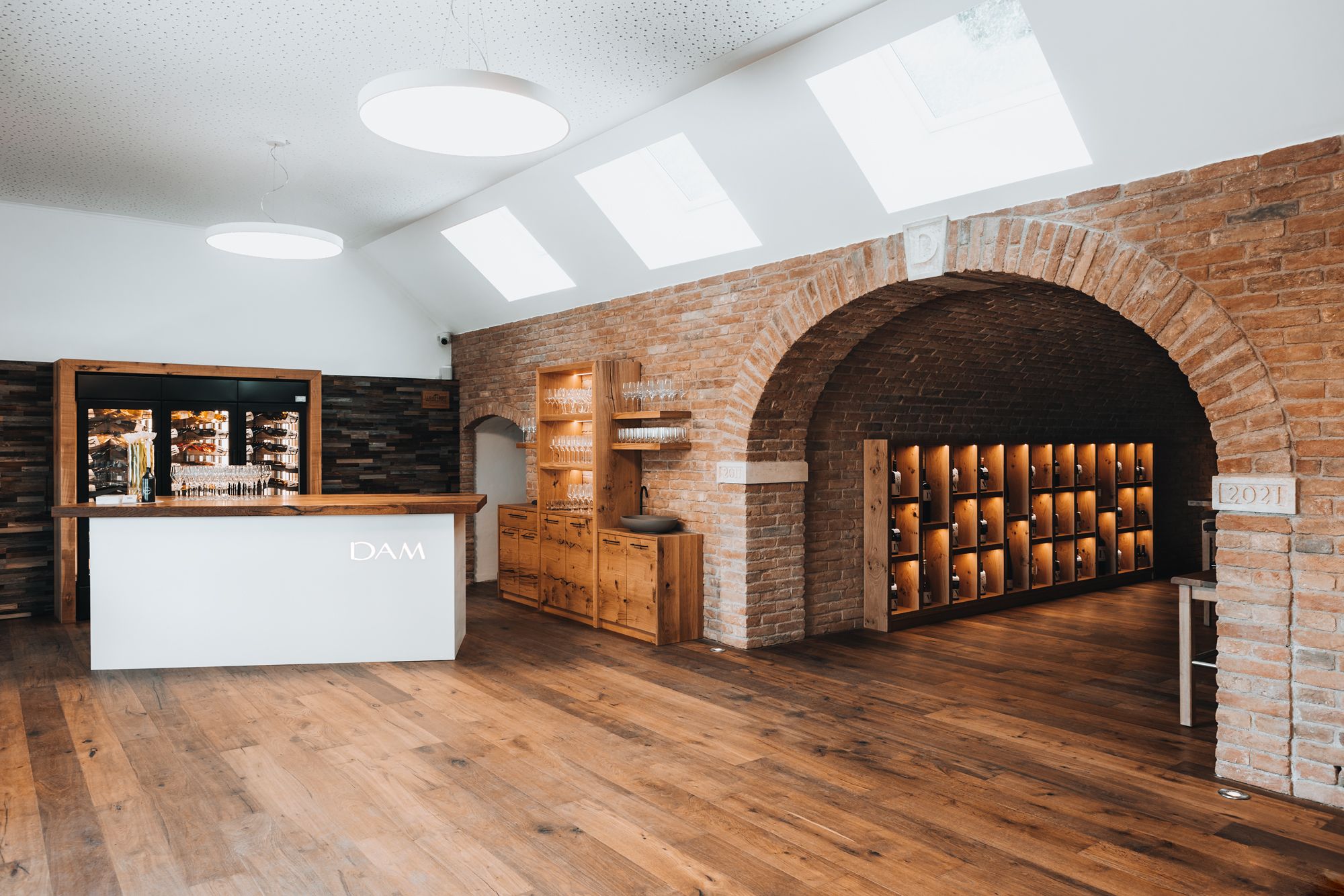 Innenansicht einer modernen Vinothek mit Holzboden, Theke und Backsteinwänden.