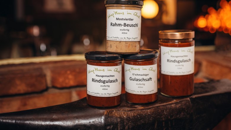 Drei Gl&auml;ser mit Fertiggerichten auf einem Amboss, beschriftet mit 'Wirtshaus im Glas'.