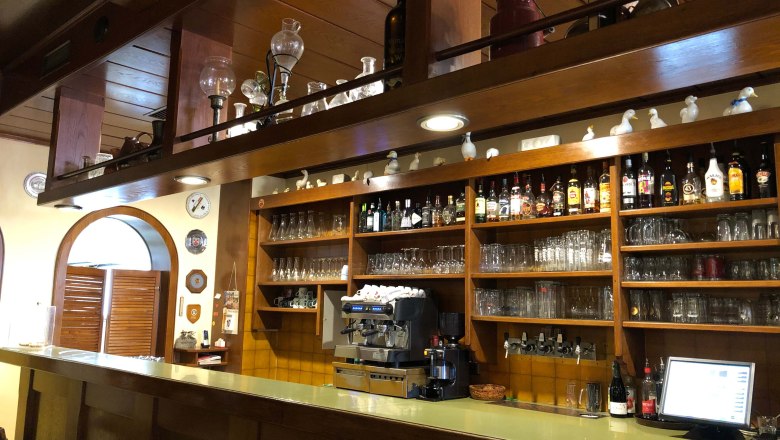 Innenansicht einer Bar mit Holzregalen, Gl&auml;sern und Flaschen.