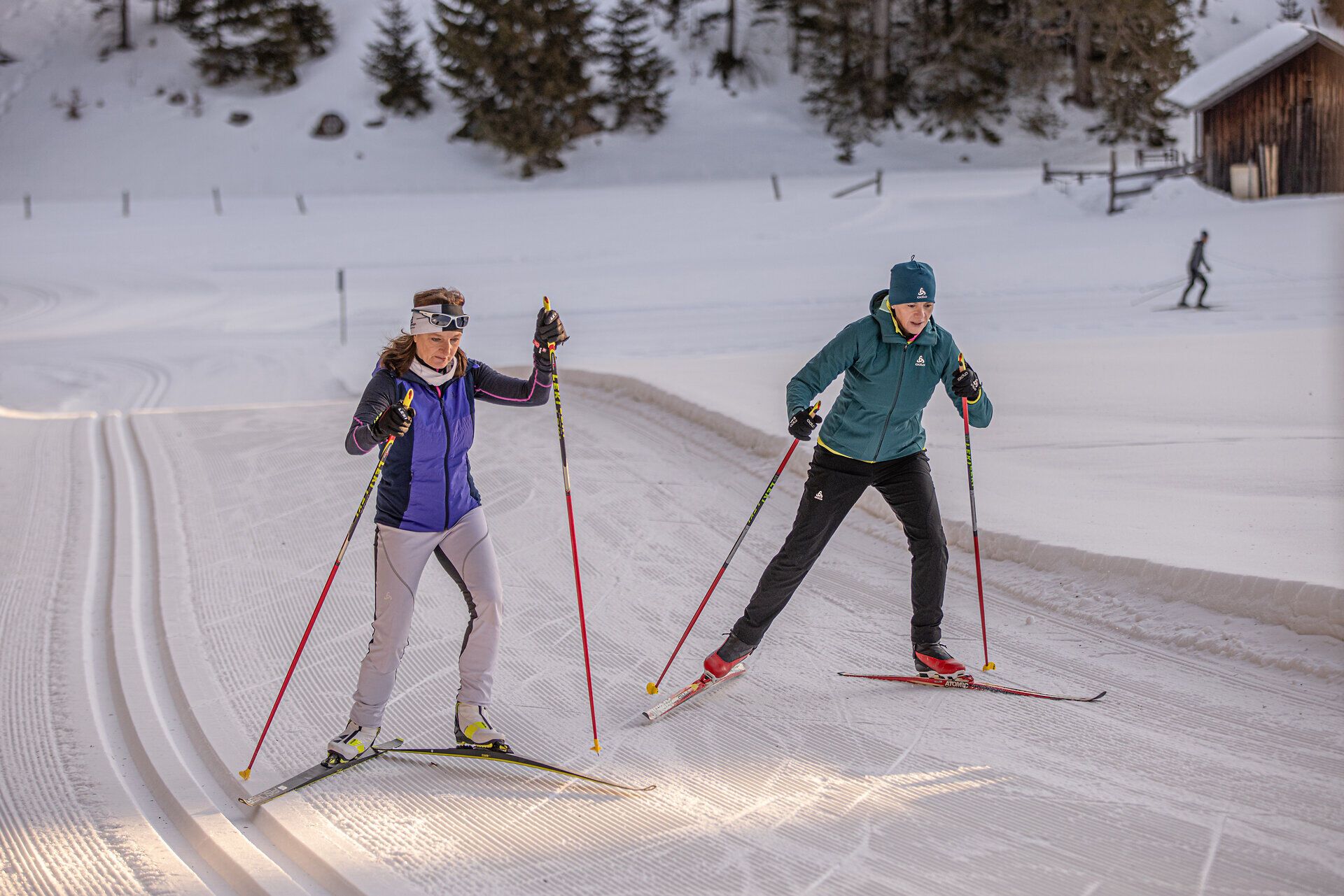 Zwei begeisterte Langläufer gleiten elegant über die schneebedeckten Loipen, umgeben von der malerischen Winterlandschaft. Die frische, klare Luft und die sanften Hügel des Mariazellerlandes schaffen eine perfekte Kulisse für unvergessliche Wintersportmomente.