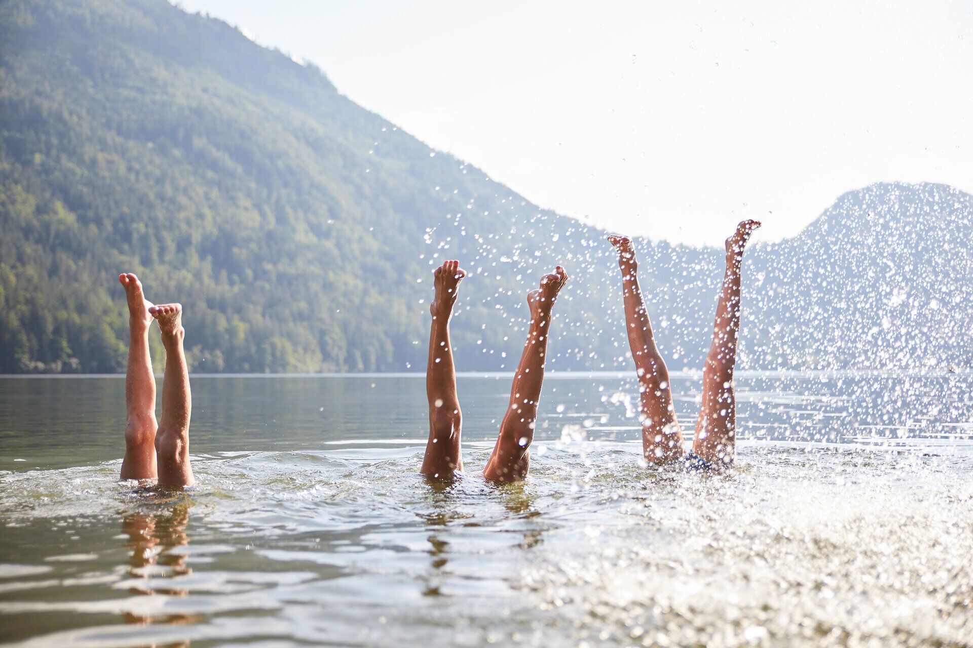 Die warmen Sonnenstrahlen tanzen auf der Wasseroberfläche, während fröhliche Menschen mit ihren Beinen im klaren Wasser planschen. Umgeben von majestätischen Bergen und üppigem Grün, vermittelt dieser Ort ein Gefühl von Freiheit und Lebensfreude. Hier wird der Sommer in seiner schönsten Form erlebt.