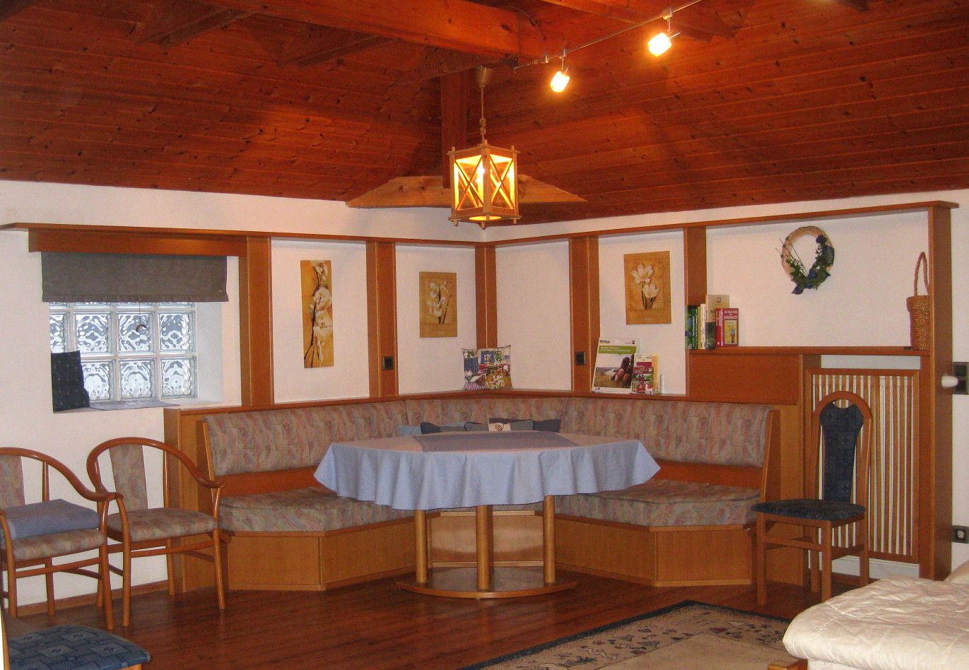 Gemütliche Sitzecke mit Holzmöbeln und blauer Tischdecke in einem Raum mit Holzdecke.