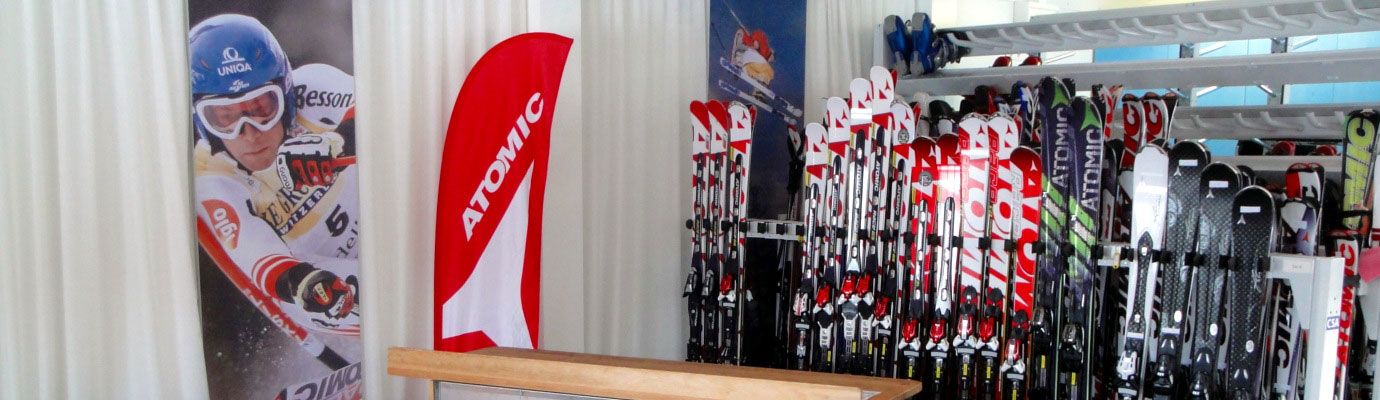 Skiverleih mit Atomic-Skiern und Werbebanner.