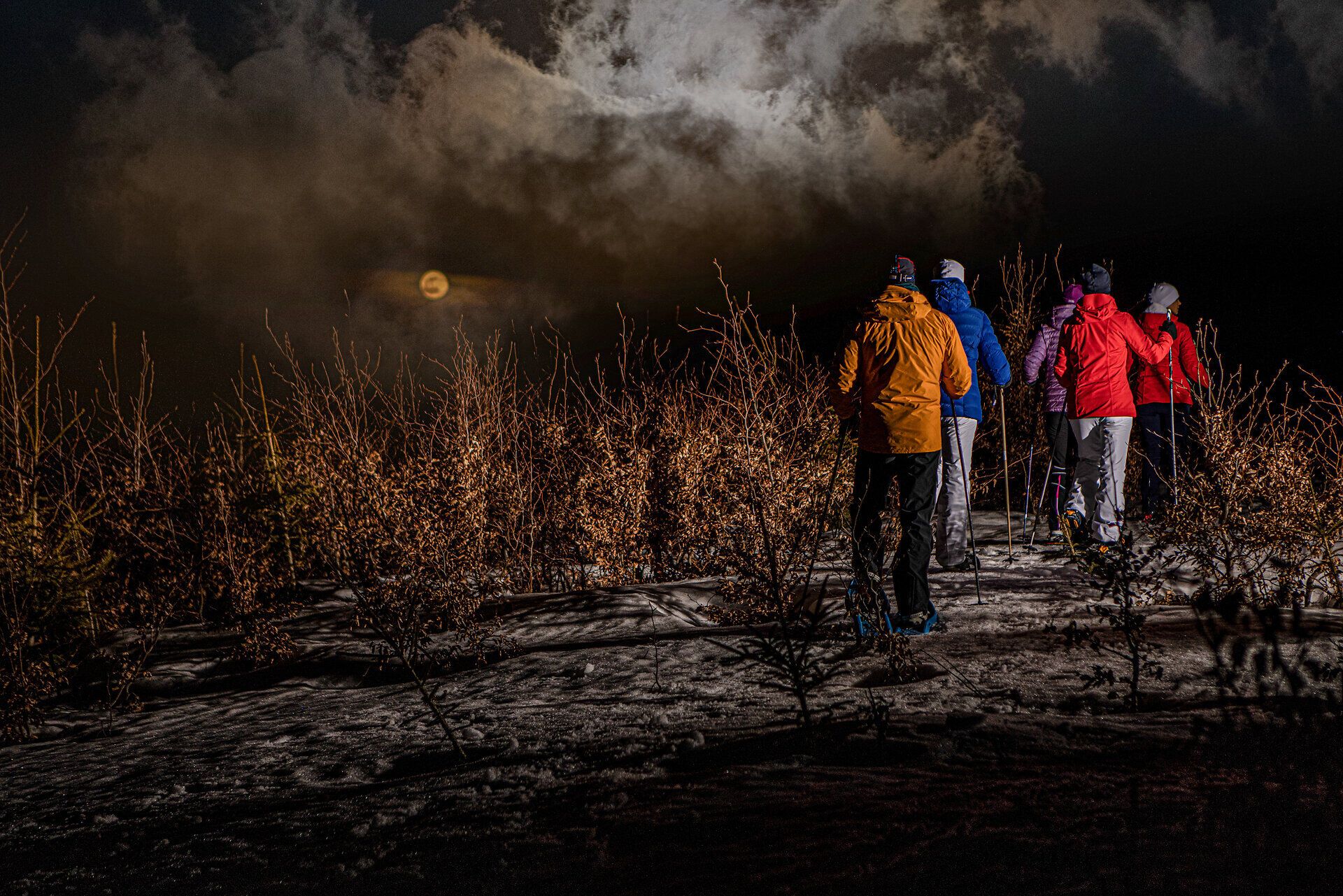 Unter dem sanften Licht des Mondes wandern die Schneeschuhläufer durch die winterliche Landschaft. Die schneebedeckten Hügel und die schimmernden Wolken schaffen eine magische Atmosphäre, die zum Verweilen einlädt. Ein unvergessliches Erlebnis in der Stille der Nacht.