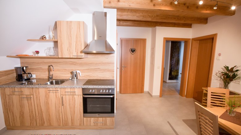 Moderne Küche mit Holzdekor, Esstisch und Blumen.